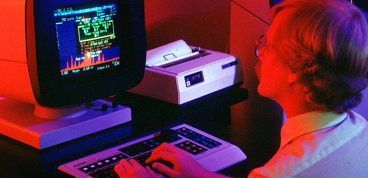 Operator at a computer console, hands on an illuminated keypad, working a data terminal